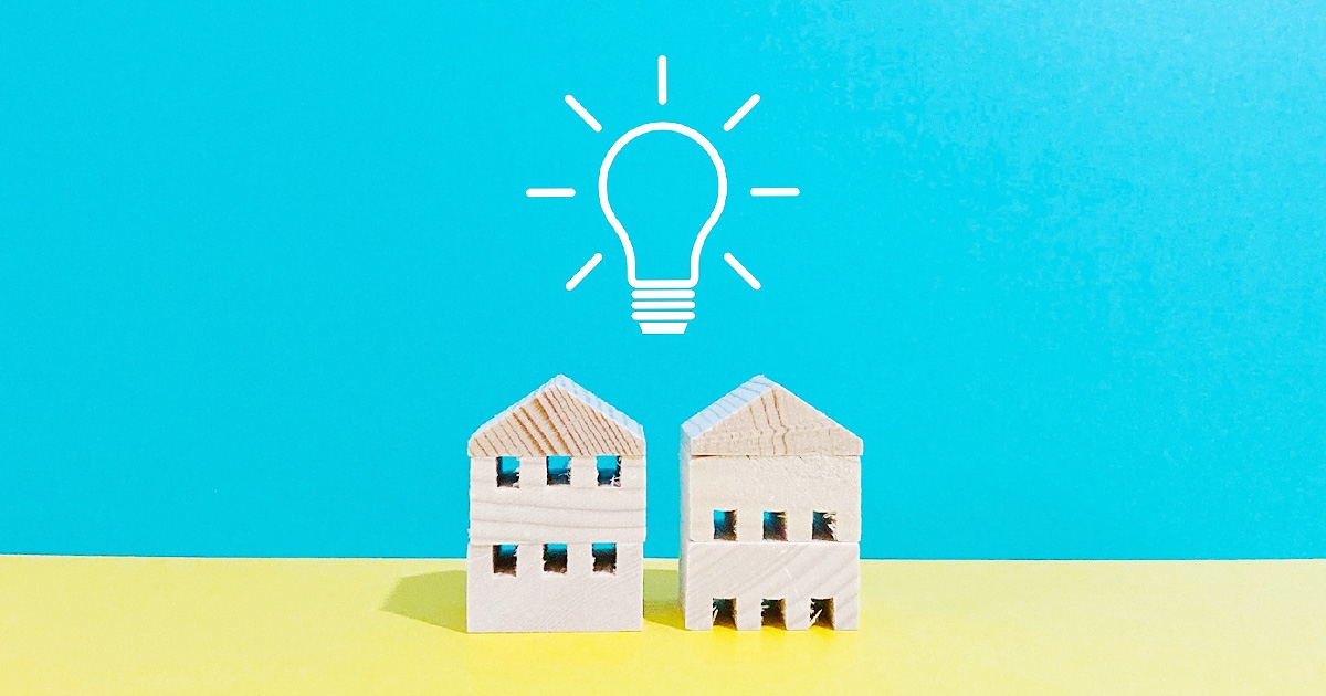 二つの家のミニチュアと電球のイラスト