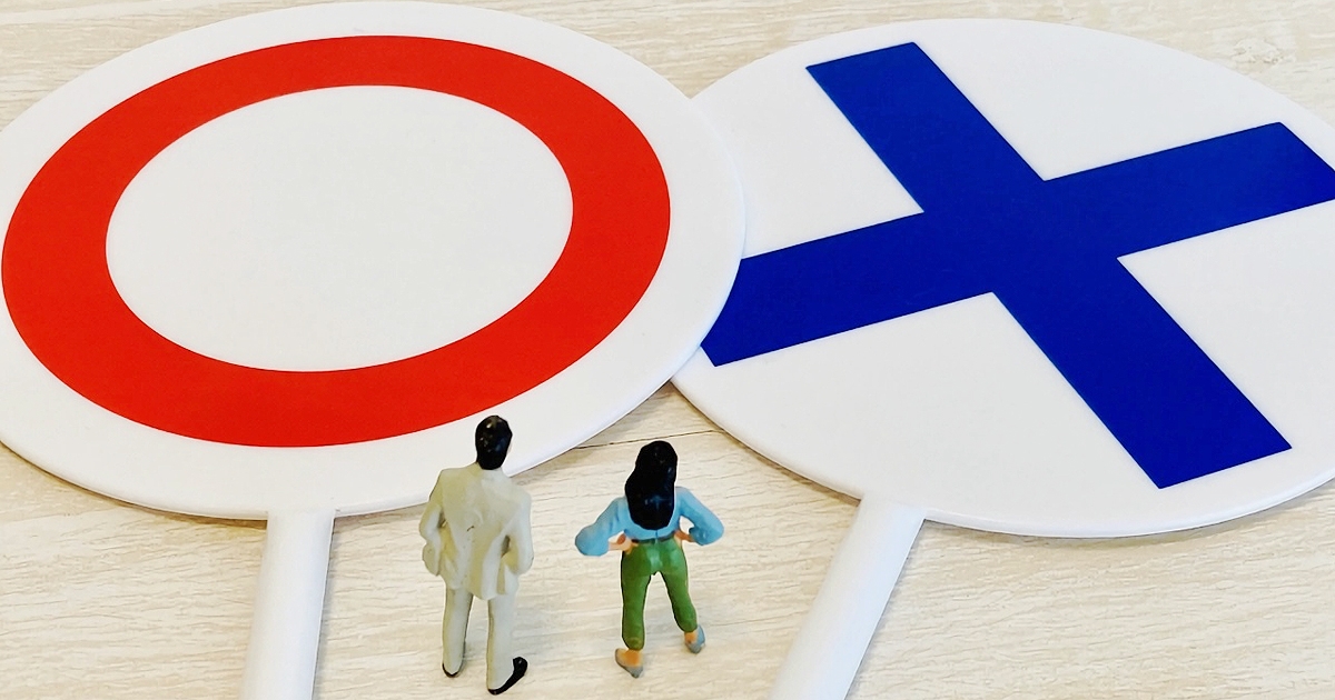 丸とバツの札を眺める男女のミニチュア