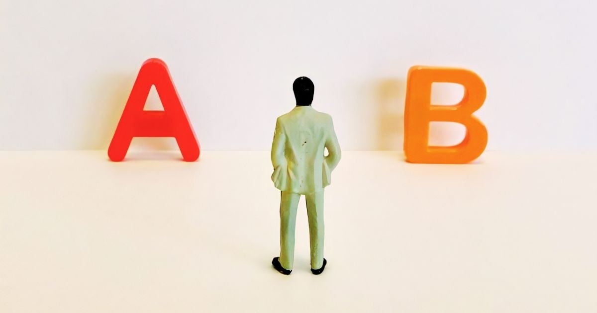 AとBの文字の間に立つ男性のミニチュア