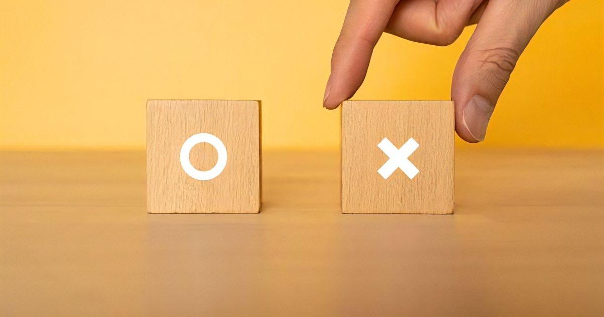 バツが描かれたブロックを持つ手